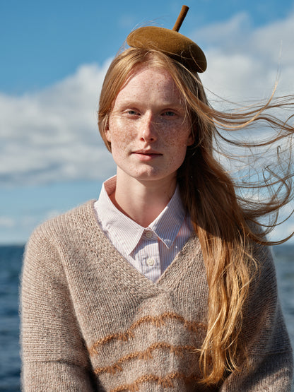 Frau mit gestricktem beigen Pullover mit V Ausschnitt